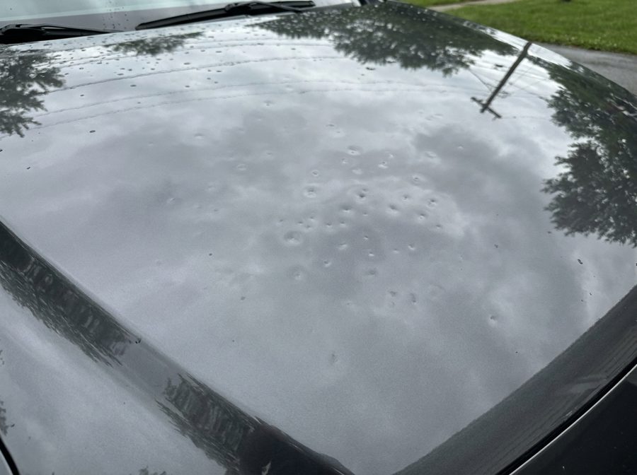 Hail damage dimples on a grey car hood before repair