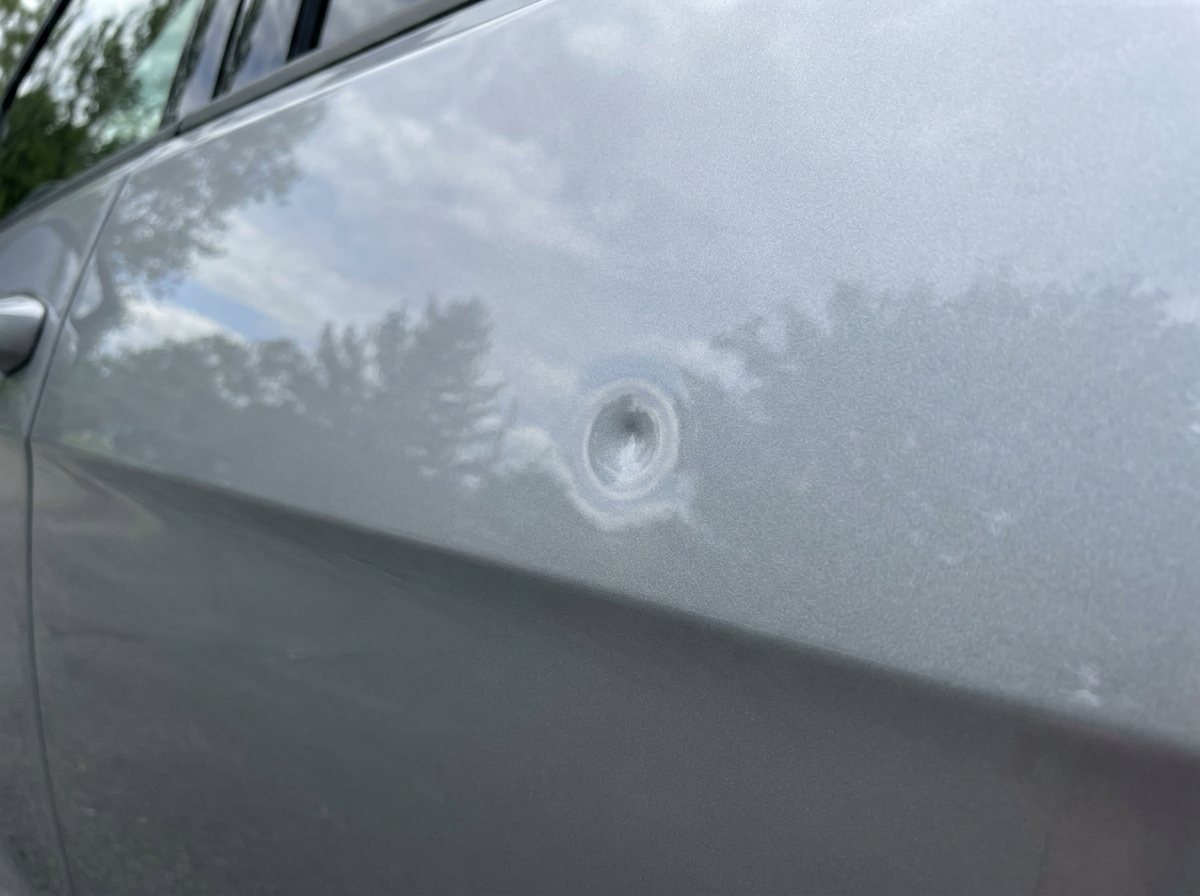 Car panel with a visible door-ding dent, before paintless dent repair